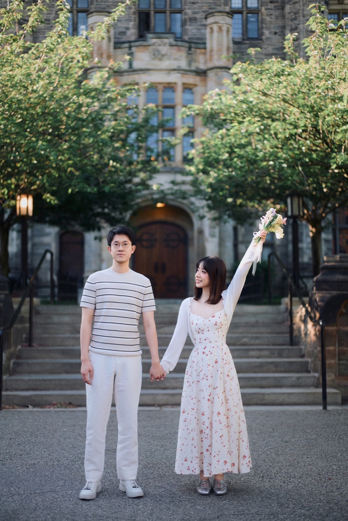 A couple holding hands with a bouquet raised in celebration