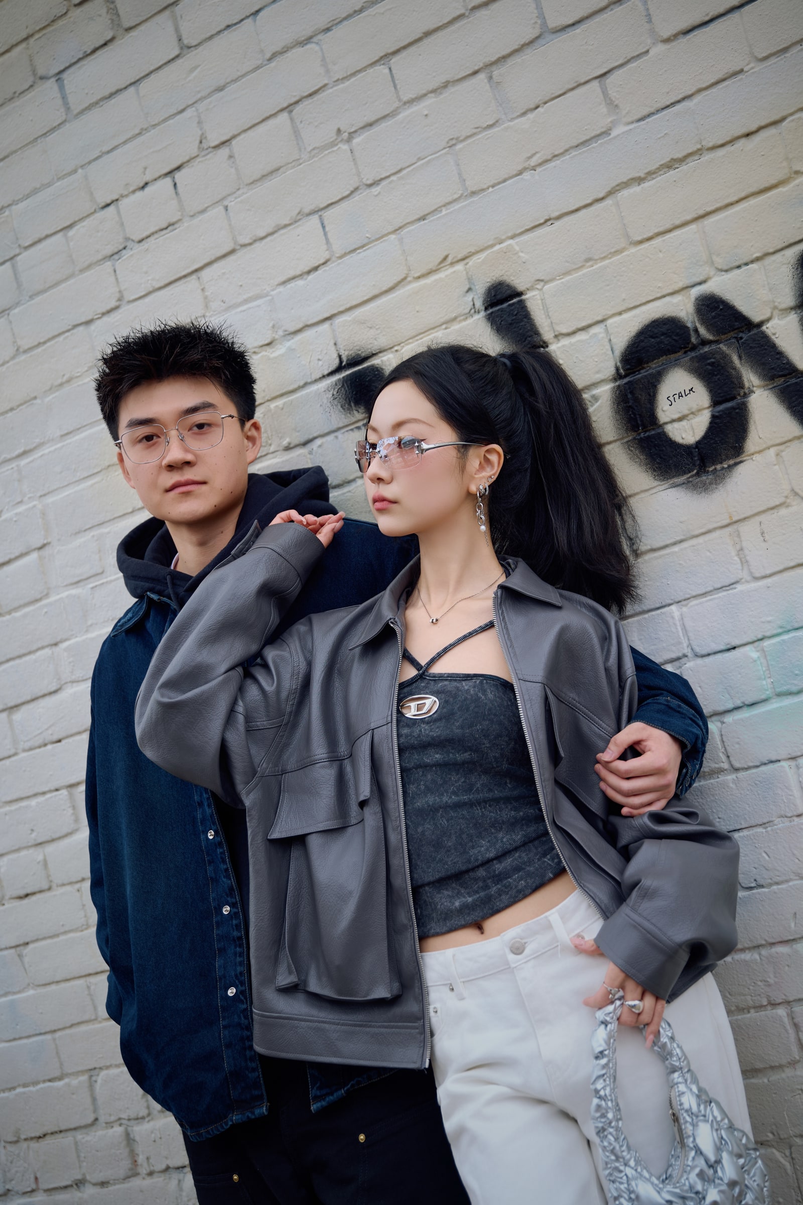A close portrait of a couple embracing beside a white brick wall