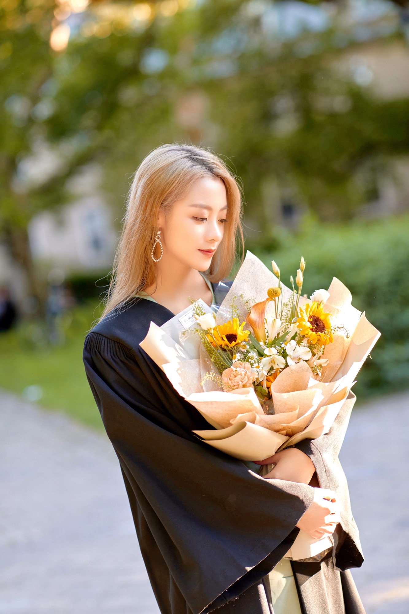 A graduate holding a bouquet in sunlight