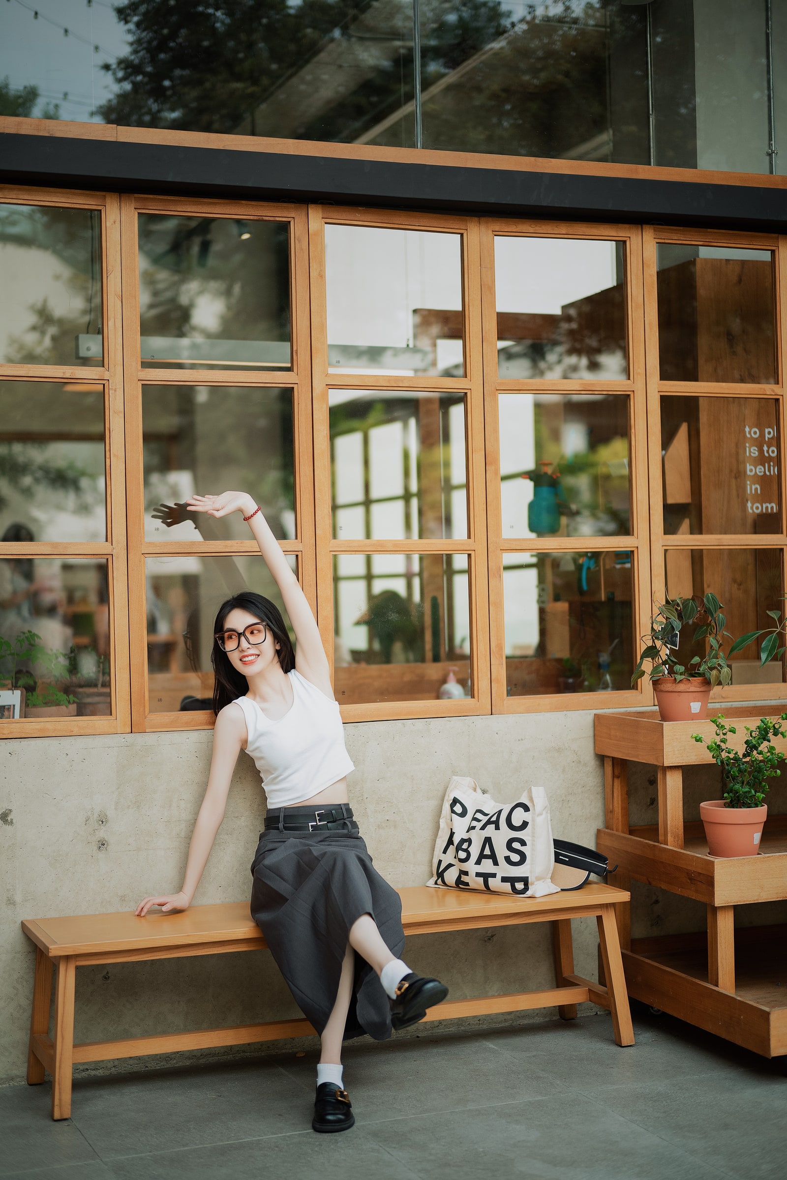 A sunlit portrait on a wooden cafe bench, with one arm raised beside the windows