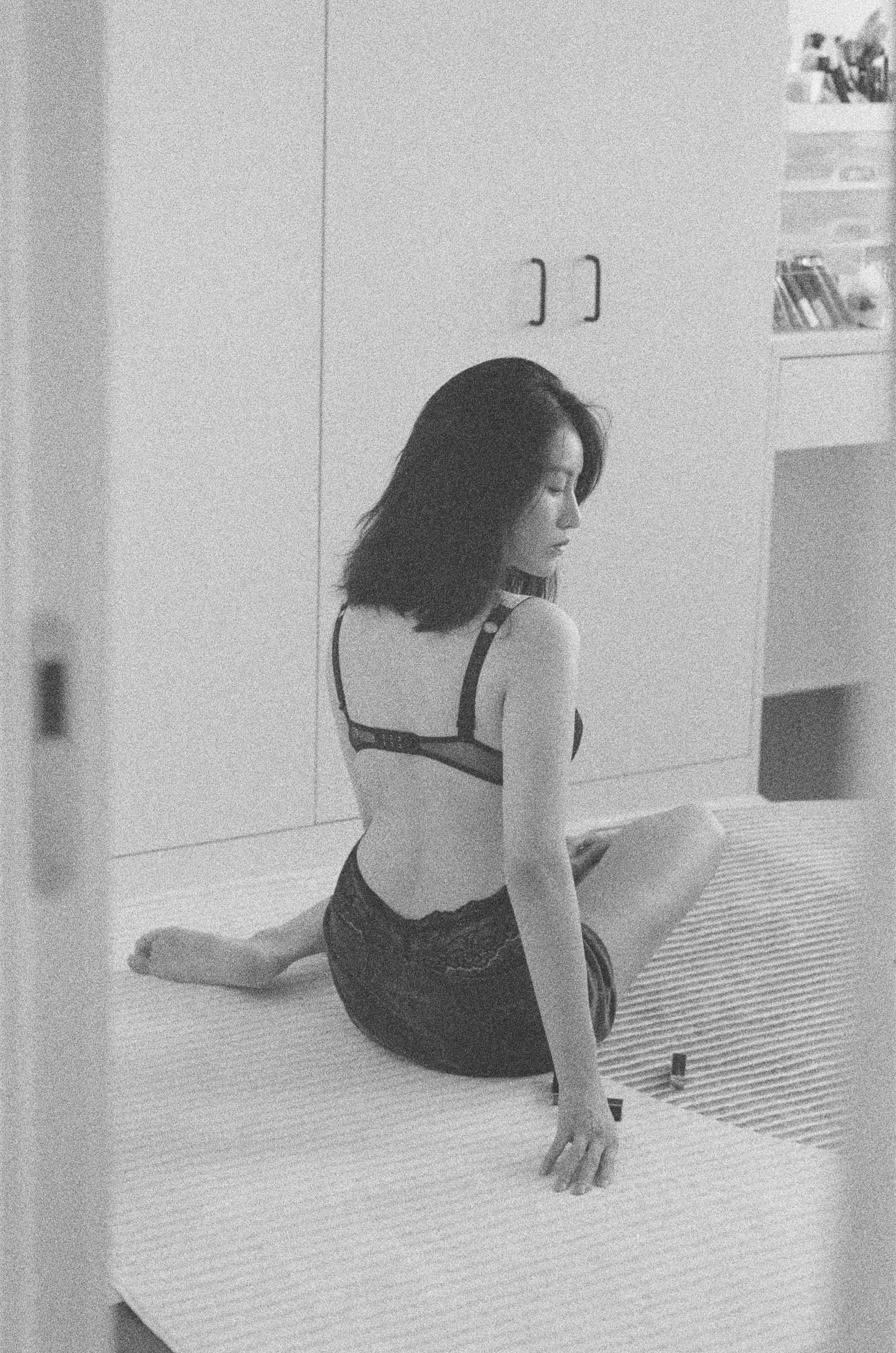 A grainy black and white portrait seated indoors, looking over one shoulder