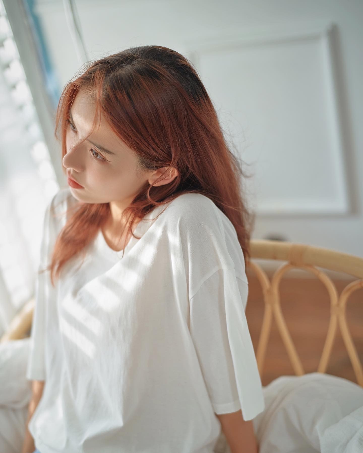 A close portrait in a white T-shirt, softly lit by a nearby window
