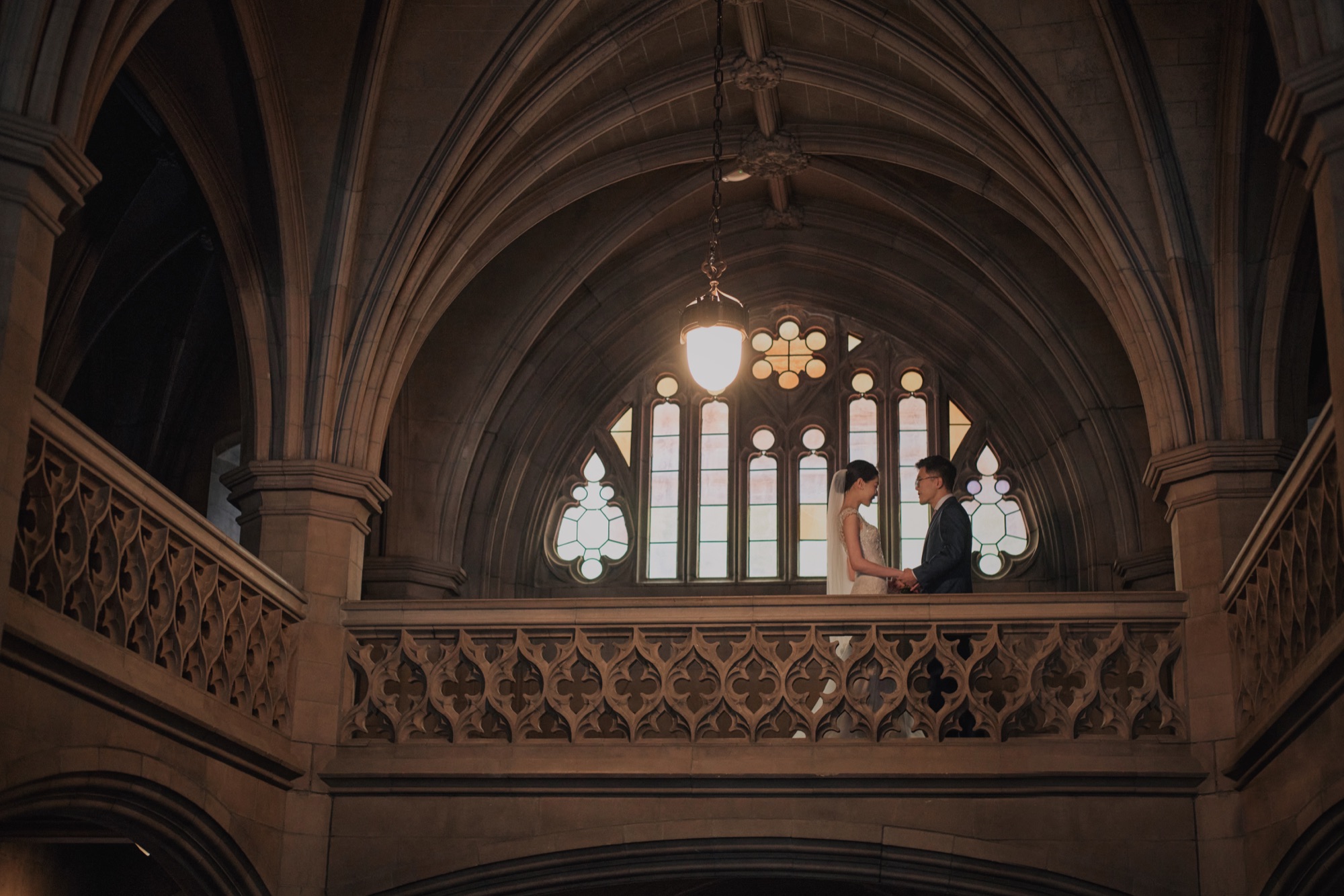 Newlyweds framed by stone arches and a tall window