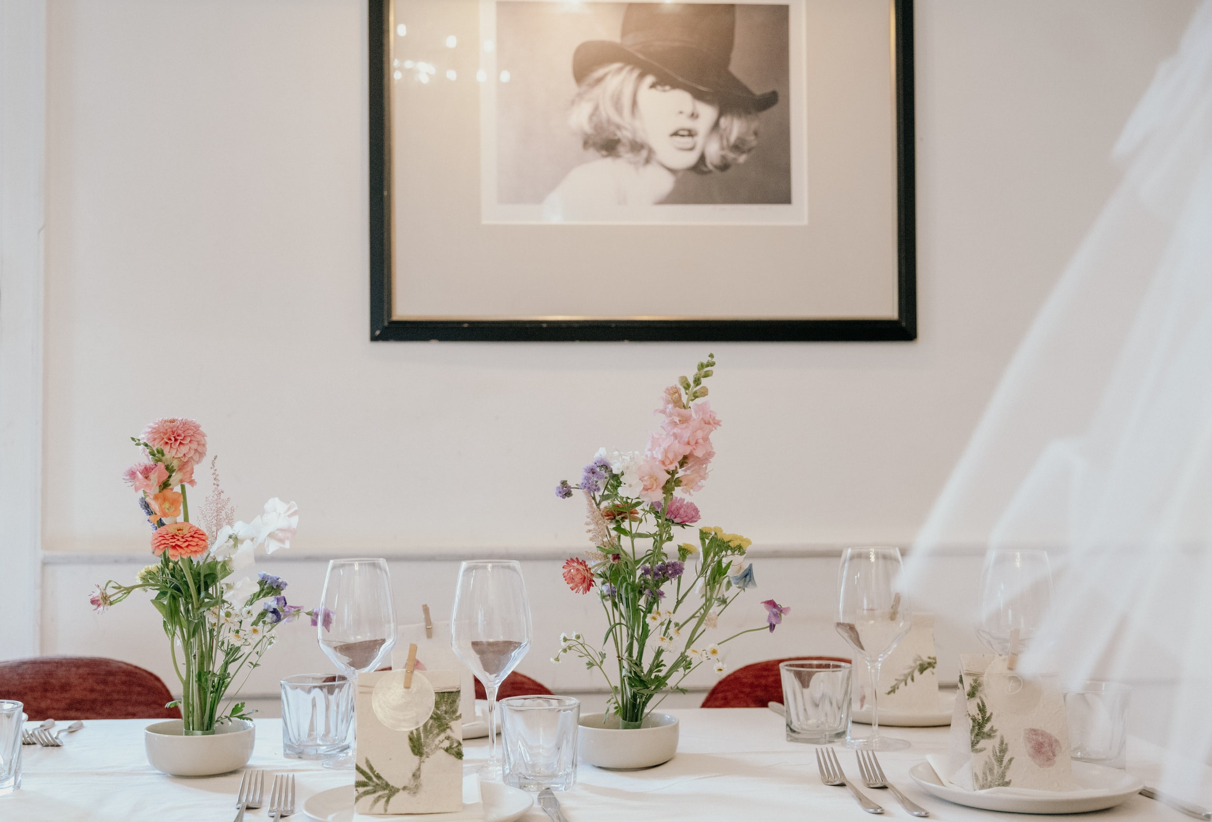 Pastel flowers and glassware on a wedding reception table in soft window light